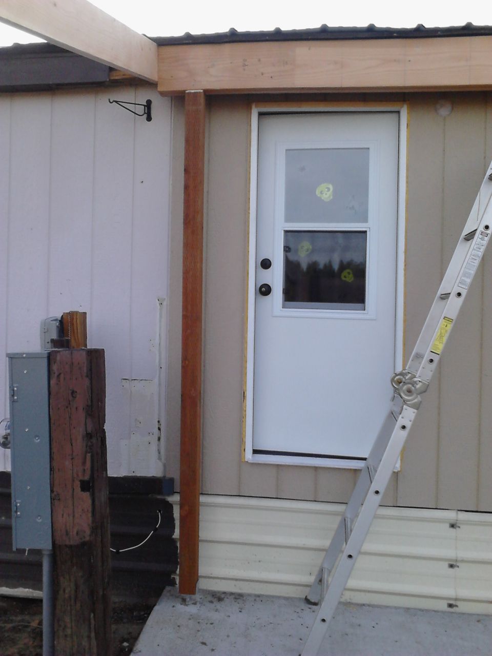 Construction scene with ladder leaning against a door, wooden beams, and electrical box