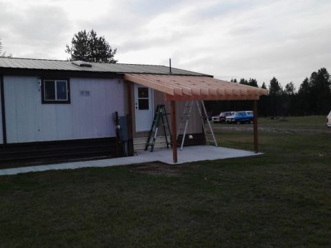 1989 Ford Bronco - A carport is under construction attached to a mobile home, with two ladders leaning against the structure. Three older model SUVs are parke…