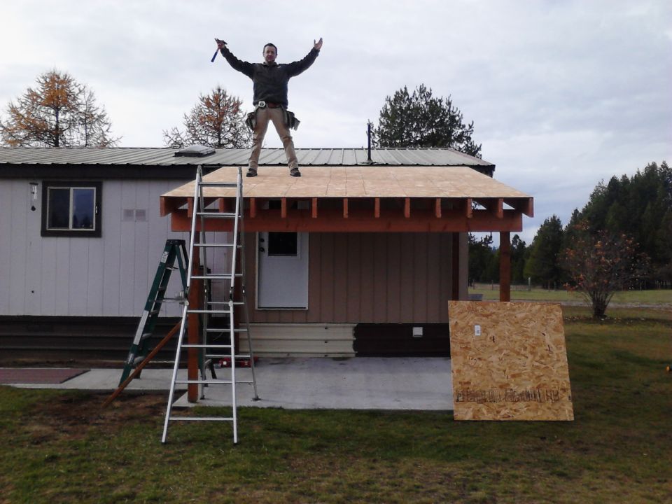 Man celebrating on a new roof with ladders nearby