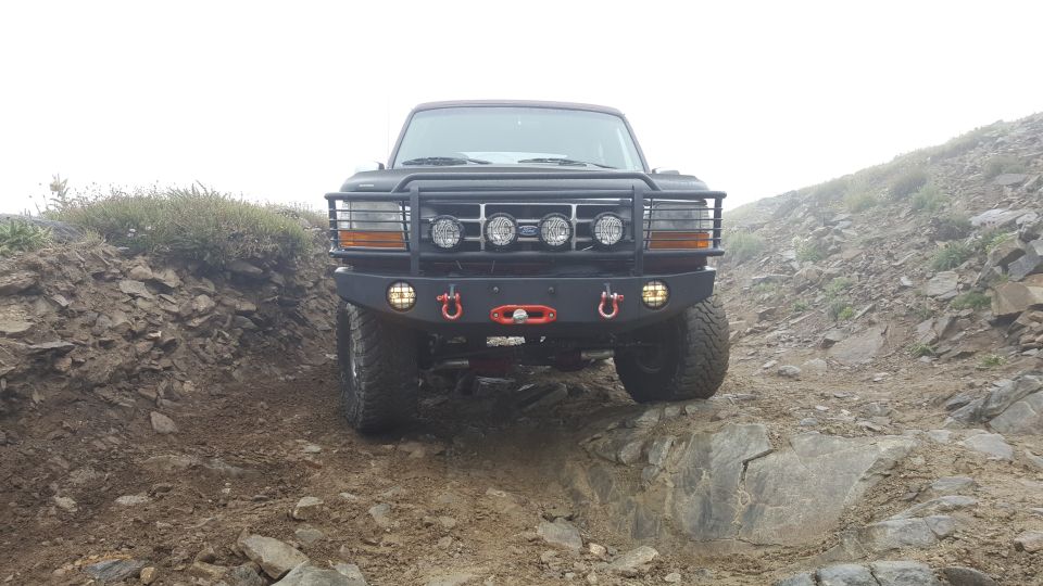1996 Ford Bronco on a rocky off-road trail with custom bumper and brush guard.