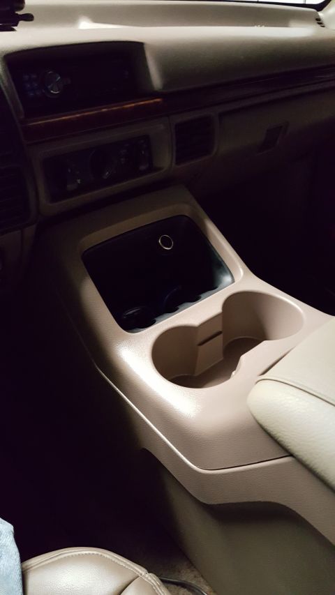 1996 Ford Bronco - The interior of a 1996 Ford Bronco shows the center console with cup holders and a storage compartment. The dashboard with radio and climat…