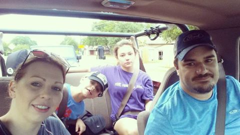 1996 Ford Bronco - A family of four is taking a selfie inside a Ford Bronco. The front passenger is a woman wearing sunglasses on her head, and the driver is…
