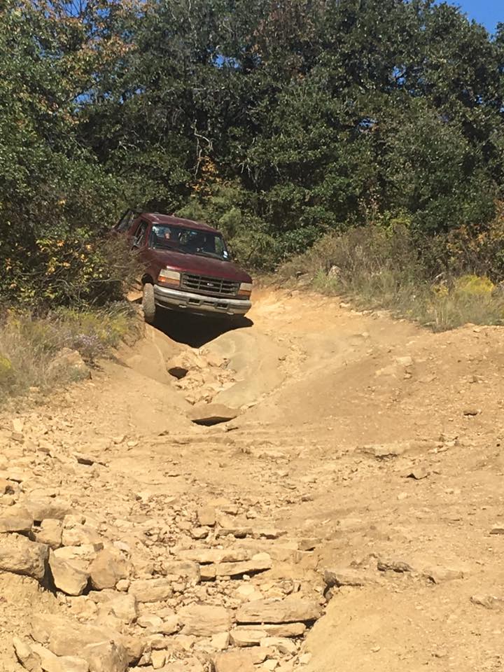 Maroon 1990s Ford Bronco on a steep, rocky dirt trail.