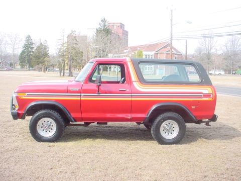 1979 Ford Bronco - This 1979 Ford Bronco is shown from the side, a red paint job with distinctive orange and yellow stripe accents.