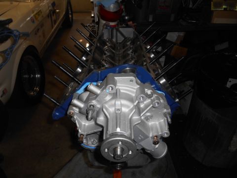 1972 Ford Bronco - A close-up view of a V8 engine block with a silver water pump assembly attached. The engine is partially assembled, with several studs prot…