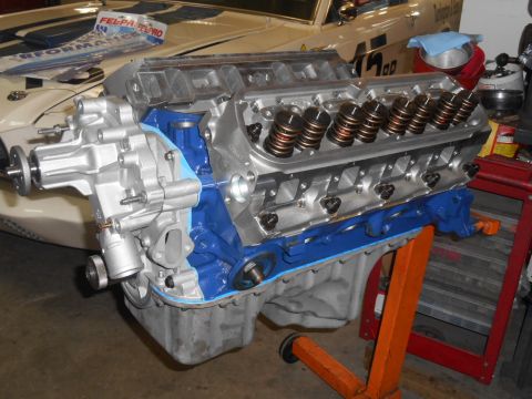 1972 Ford Bronco - A close-up view of a rebuilt V8 engine, painted blue and silver, mounted on an orange engine stand. The engine is partially assembled, show…