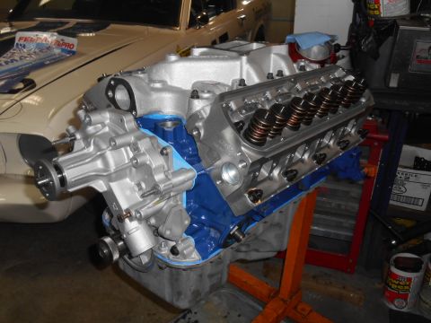 1972 Ford Bronco - A Ford V8 engine, painted silver and blue, is mounted on an orange engine stand. The engine is partially assembled, with valve springs visi…