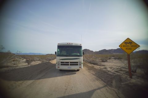 1995 Chevrolet P30 1 Ton - Step Van - A white Class A RV is parked on a dirt road in a desert landscape. A yellow diamond-shaped sign reading "4 WHEEL DRIVE ROAD" is visible to…
