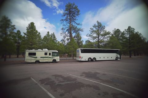 1995 Chevrolet P30 1 Ton - Step Van - A cream-colored RV is parked in a lot next to a white tour bus. Both vehicles are surrounded by tall pine trees under a partly cloudy blue…