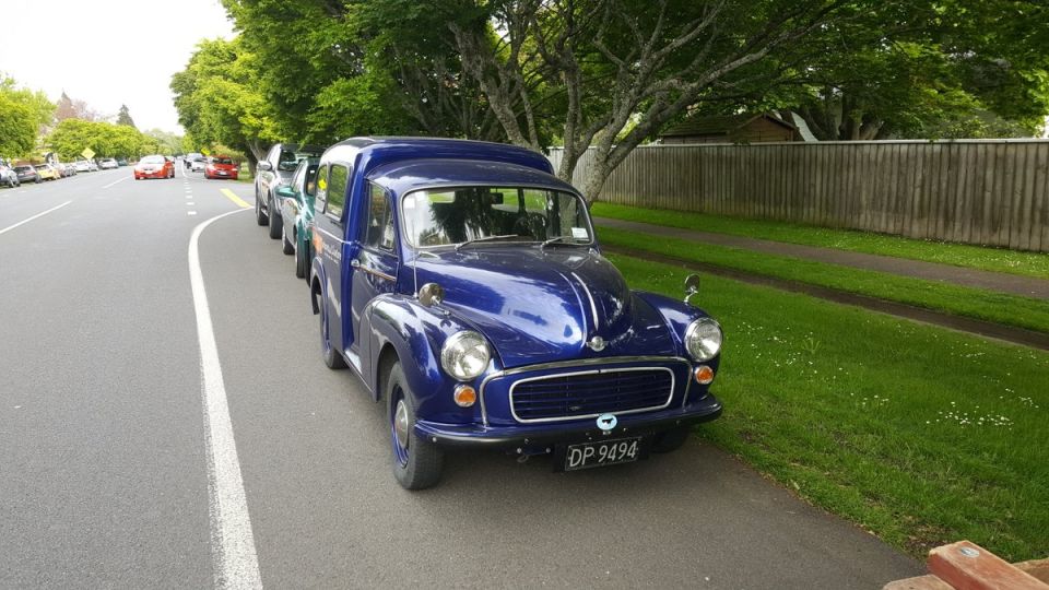 Blue vintage panel van parked on a street.