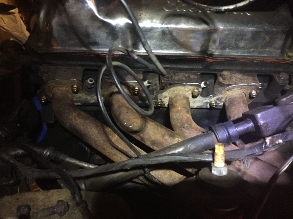 Rusty exhaust manifold and spark plug wires on a V8 engine.