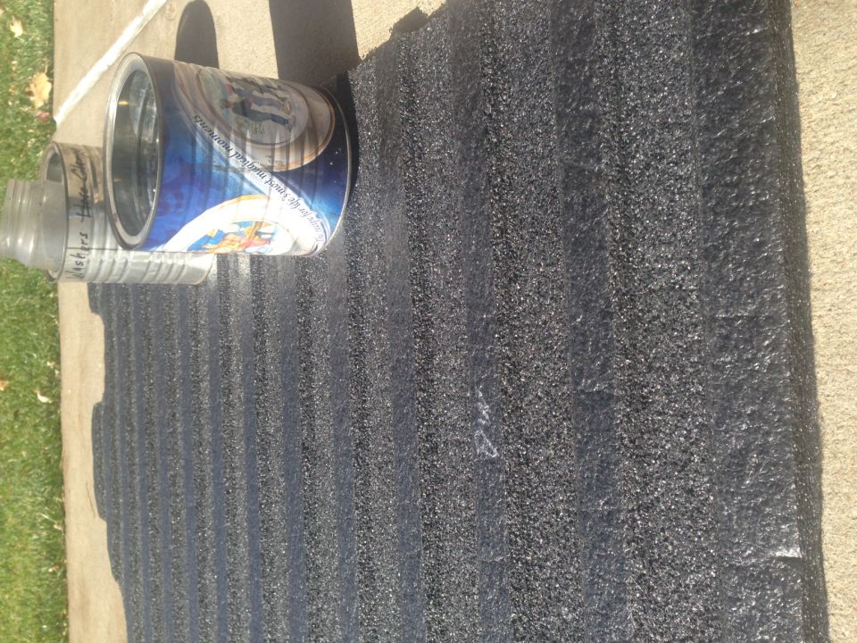 Two empty cans on a black textured mat.