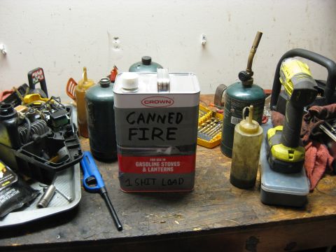 1994 Ford Bronco - A collection of items including a can labeled "CANNED FIRE" for gasoline stoves and lanterns, a propane torch, a cordless drill, and a disa…