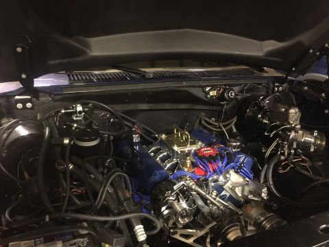 1982 Ford Bronco - A detailed view of a modified V8 engine bay, featuring a blue intake manifold, red MSD ignition wires, and polished chrome components. The…