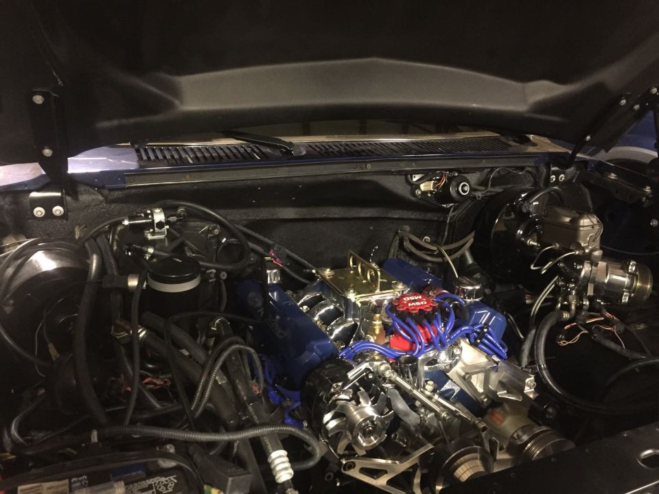 Modified V8 engine bay with blue intake, red MSD wires, and chrome parts.