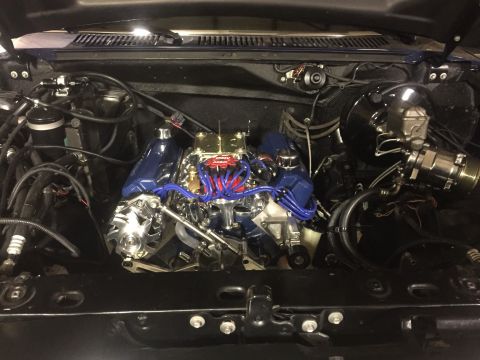 1982 Ford Bronco - A detailed, high-angle view of a modified V8 engine installed in a vehicle's engine bay. The engine features polished aluminum valve covers…
