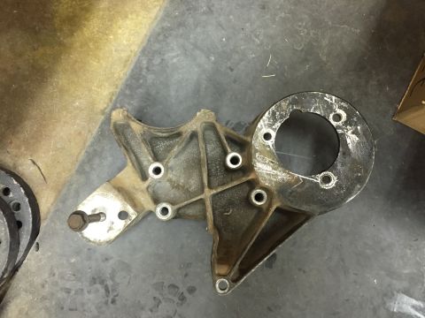 1988 Ford Bronco - A cast aluminum bracket with a circular flange is shown mounted to a dark, textured surface. The bracket has several bolt holes and a singl…