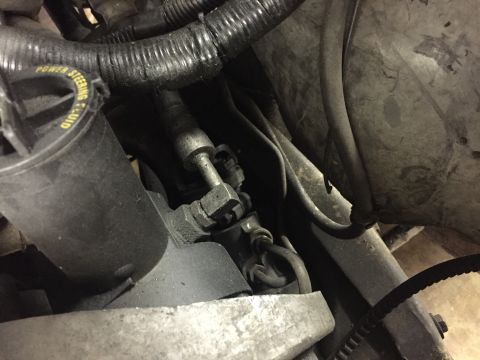 1988 Ford Bronco - A close-up view of the power steering fluid reservoir cap and associated hoses in an engine bay. The cap is black with yellow text that rea…