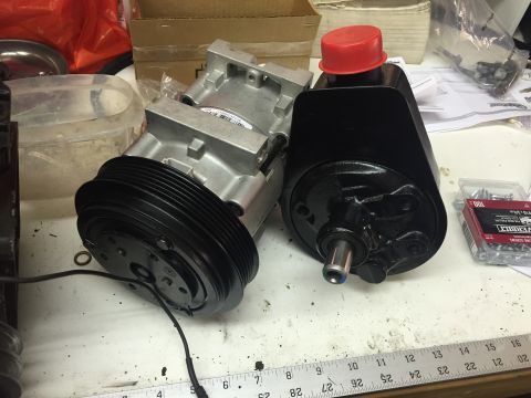 1988 Ford Bronco - Two automotive parts, likely an air conditioning compressor and a power steering pump, are shown on a workbench. The air conditioning compr…