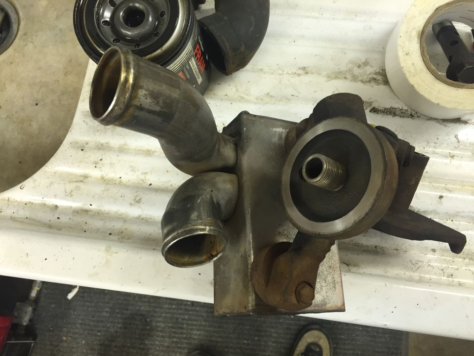 Rusty oil cooler assembly with metal pipes, Fram oil filter, and tape.