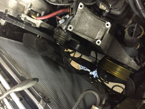 1988 Ford Bronco - A close-up, high-angle view of the engine bay of a Ford Bronco, focusing on the serpentine belt system and the front of the radiator.