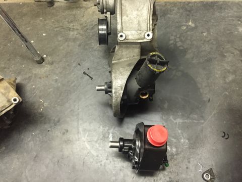 1988 Ford Bronco - A disassembled power steering pump is shown on a concrete floor next to a larger, unidentifiable automotive component. The power steering p…