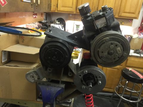 1988 Ford Bronco - A black air conditioning compressor assembly is mounted to a bracket and held in a vise. The assembly includes two pulley systems and a fil…
