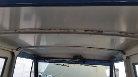 1973 Ford Bronco - Interior view of the roof and windshield area of a classic vehicle, showing the metal ceiling, windshield wipers, and the top of the windsh…
