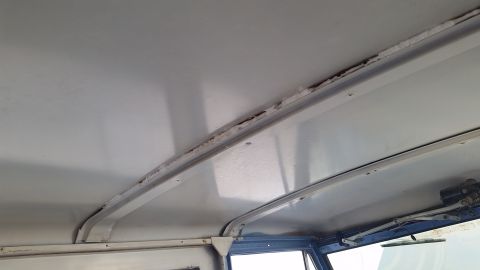 1973 Ford Bronco - Interior view of a vehicle's headliner, showing metal support beams and evidence of water damage or rust along the seams.