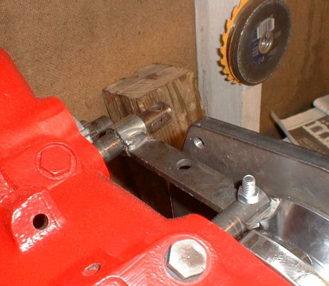 1990 Ford Bronco - Close-up of a red metal component with linkage, near a grinder and wood block.
