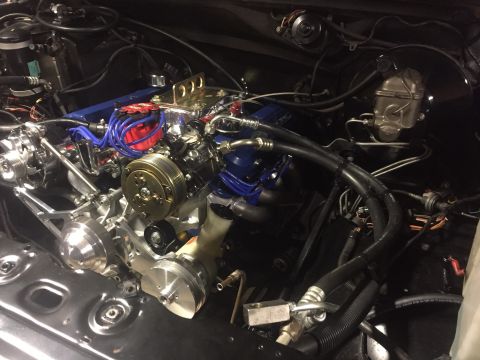 1982 Ford Bronco - A highly detailed, custom engine bay is shown, featuring a polished aluminum intake manifold, bright blue spark plug wires, and chrome acce…