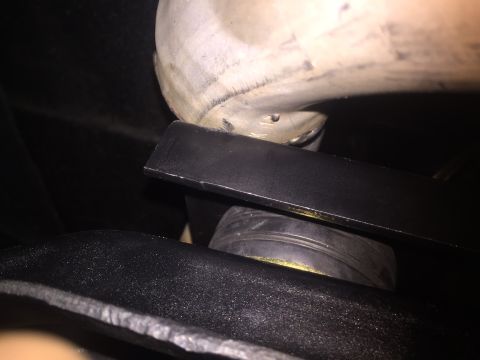1982 Ford Bronco - A close-up, low-angle shot shows a black metal bracket positioned above a black rubber component, likely a suspension part, on a vehicle.