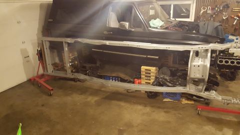 1994 Ford Bronco - A black Ford Bronco body is shown disassembled, with the frame and engine block visible in a garage setting. The vehicle is supported by re…