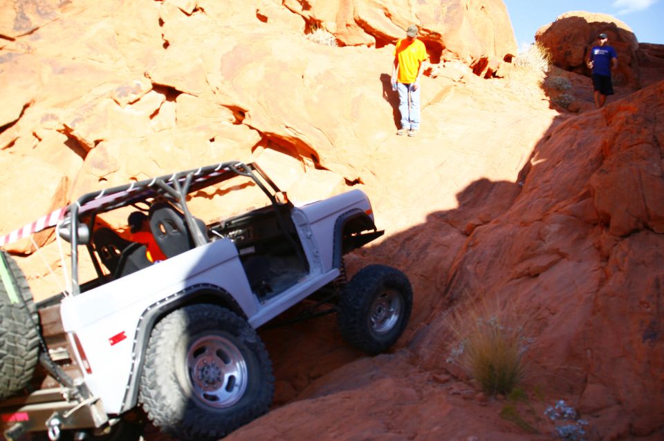 White Ford Bronco climbing a steep, rocky off-road trail.