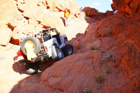 1979 Ford Bronco - A white Ford Bronco is navigating a steep, rocky incline in a desert landscape. The vehicle is angled upwards, with its rear facing the cam…