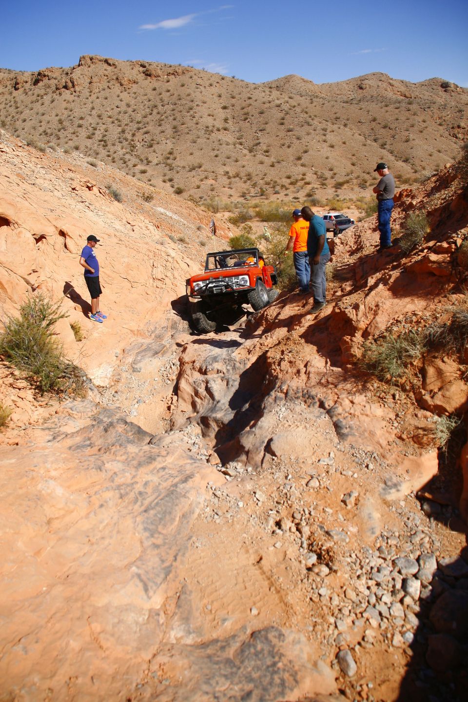 Orange Ford Bronco on a steep, rocky off-road trail.
