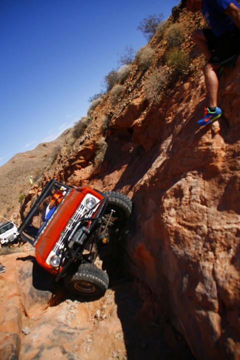 1979 Ford Bronco - An orange Ford Bronco is tilted precariously on a steep, rocky incline, with its front wheels off the ground. The vehicle appears to be nav…