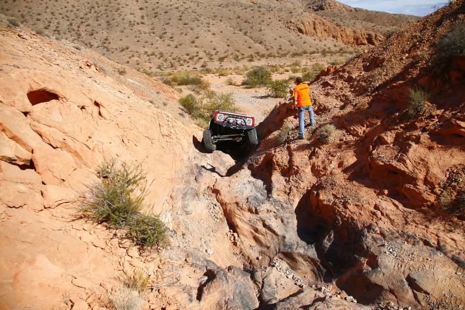 1979 Ford Bronco navigating a steep, rocky canyon with a person watching from above.