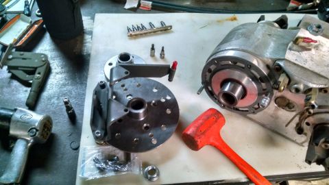 1985 Jeep CJ7 - A workbench displays disassembled parts of a vehicle, including a metal housing unit, a circular flange with multiple holes, and various to…
