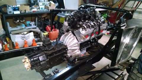 1985 Jeep CJ7 - A modified Jeep CJ7 chassis is shown with a V8 engine and transmission assembly installed. The vehicle is in a workshop setting with variou…