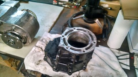 1985 Jeep CJ7 - A disassembled engine part, likely a cylinder block, sits on a workbench next to another metal engine component. The scene appears to be a…