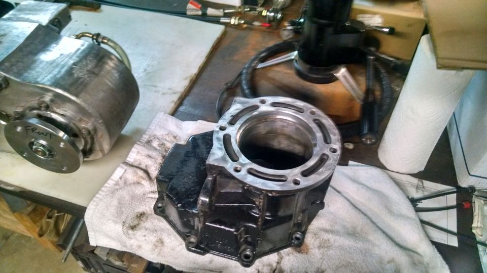 Disassembled engine block and cylinder on a workbench.