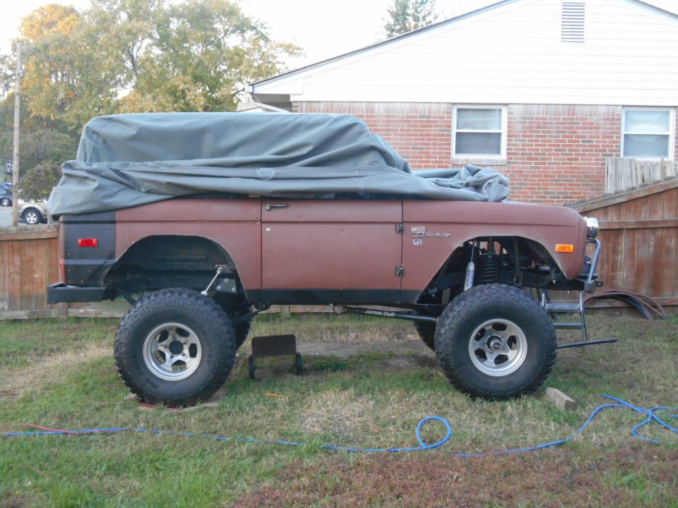1972 Ford Bronco covered with a tarp, lifted with large tires