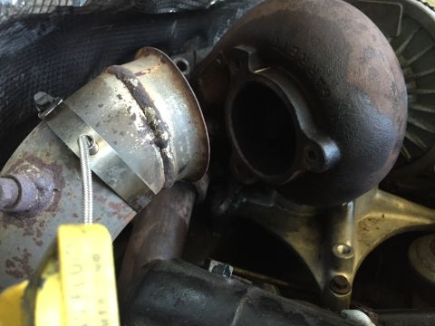1997 Ford F-350 - Close-up of a turbocharger and exhaust pipe, with a yellow tag attached to the pipe.