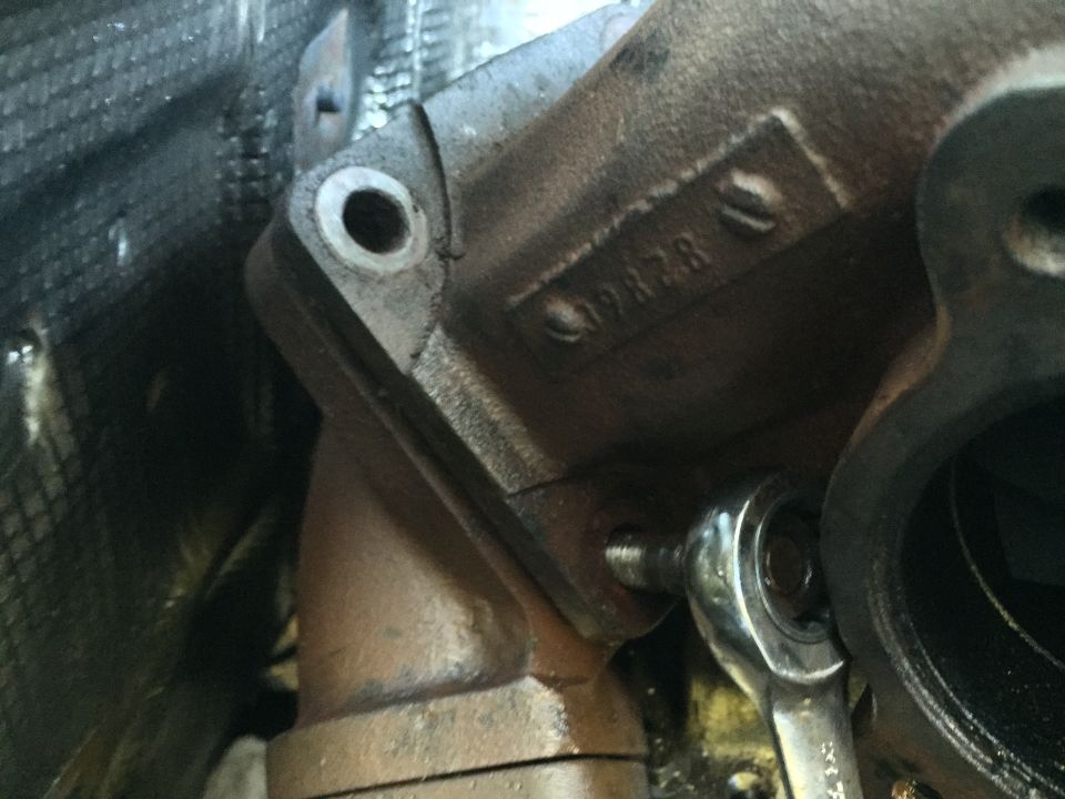 Close-up of a turbocharger component with stamped numbers '19828' and a socket wrench