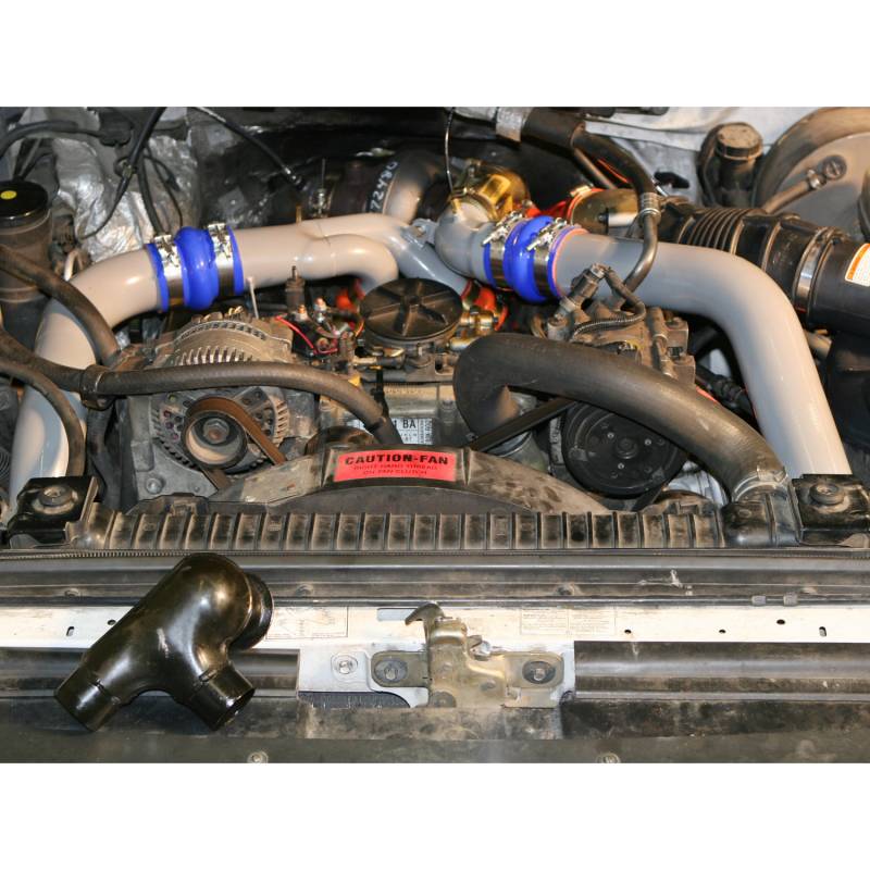1997 Ford F-350 engine bay with turbo piping and a 'Caution-Fan' sticker