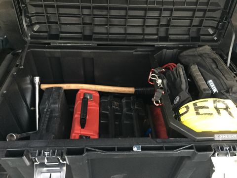 1988 Ford Bronco - Contents of a vehicle's storage box, including tools and safety equipment.