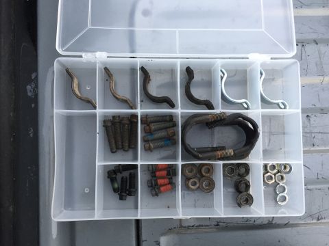 1988 Ford Bronco - A clear plastic organizer contains a collection of automotive hardware, including bolts, nuts, and metal clips.