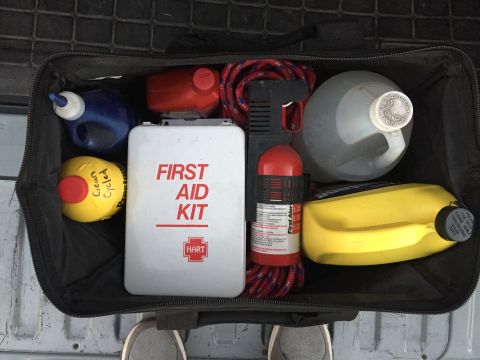 1988 Ford Bronco - A storage bag contains a first aid kit, fire extinguisher, rope, and several containers of fluids, likely for vehicle maintenance or emerge…