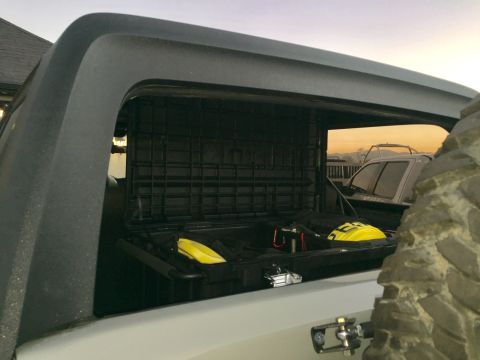 1988 Ford Bronco - A storage box is open in the bed of a truck, with another vehicle parked behind it.
